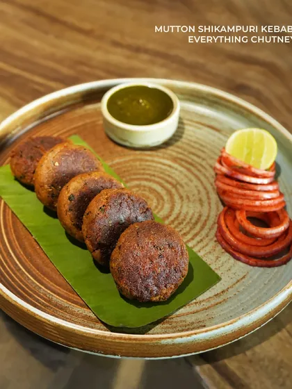 Mutton Shikampuri Kebab, a tender, pan-fried kebab with a surprise yogurt filling. Served with our 'everything chutney,' it's a classic dish executed with finesse.