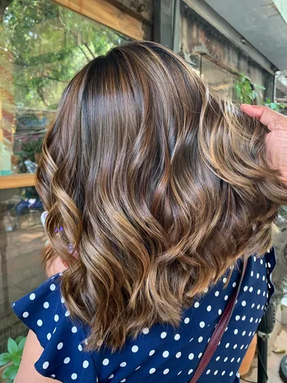 Here’s to living in the glow. This short, wavy bob with caramel highlights is a perfect example of a non-bleach color that makes a big impact.