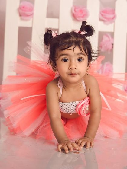 Our little butterfly. This adorable first birthday theme uses a pink tutu, fairy wings, and a cute picket fence for a magical garden party feel.