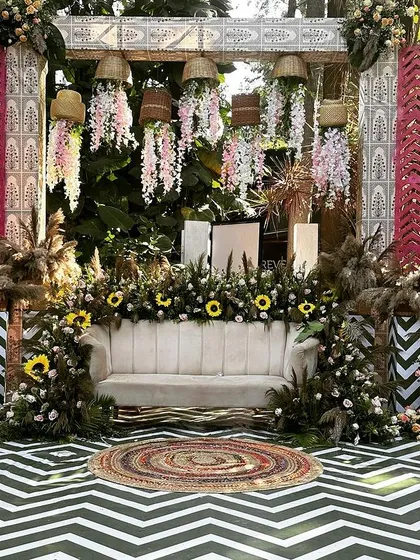 A full view of a stunning boho-themed Mehendi stage, featuring a mix of textures like pampas grass, chevron patterns, and macrame.
