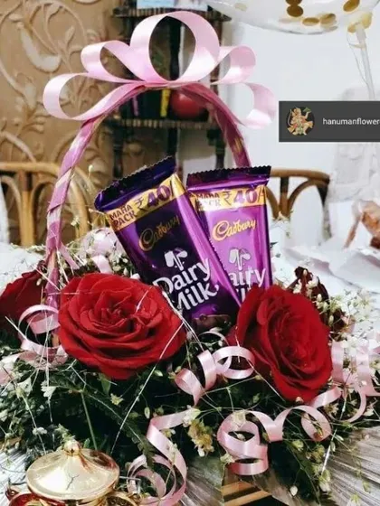 A charming and sweet gift basket perfect for any occasion. This arrangement features rich red roses and two bars of Cadbury Dairy Milk chocolate, all tied together with a beautiful pink ribbon.
