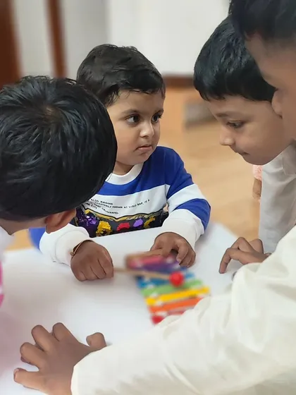 Children of different ages gather around a single activity, demonstrating the cooperative spirit of our mixed-age classrooms. The environment encourages collaboration and peer learning.