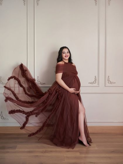 A full-length shot of the Renee gown. The off-shoulder design and ruffled trail create a dramatic and beautiful silhouette.