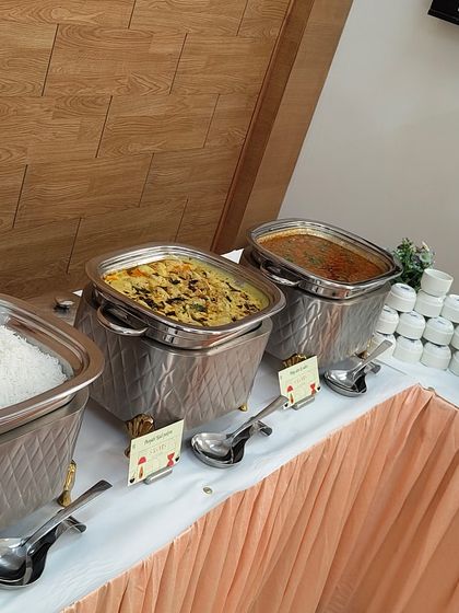 A view of the main course station at a corporate lunch, with various Indian curries and rice ready to be served.
