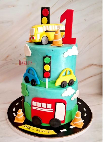 An automobile-themed cake for Sabir turning one! This fun, two-tier cake features colorful cars, a school bus, and traffic lights. It was a dark chocolate and strawberry flavor, perfect for a kids' party.