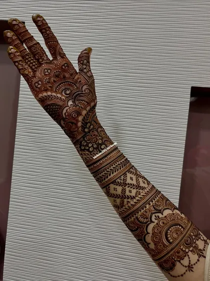 A full-arm bridal mehendi, rich with traditional Indian motifs. The design flows from the palm to the elbow, creating a seamless and elegant look.
