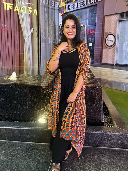 Here, a vibrant printed shrug adds life to a simple black jumpsuit. This demonstrates how a single statement piece can transform an entire outfit for a festive or casual event.