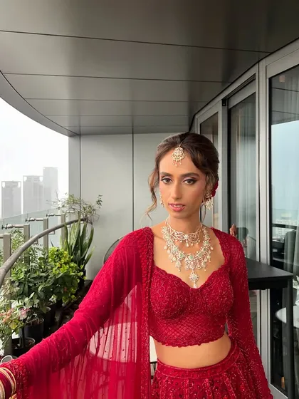 This bride is ready for her ceremony, with her floral bun providing a stunning focal point that complements her red lehenga perfectly.