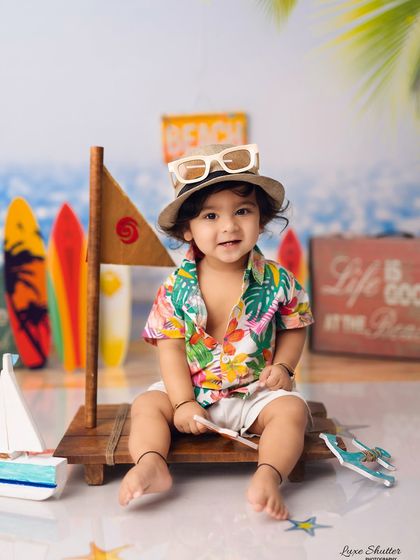 A slightly different angle showing the full beach setup, including the surfboard props and "Life is Good at the Beach" sign.