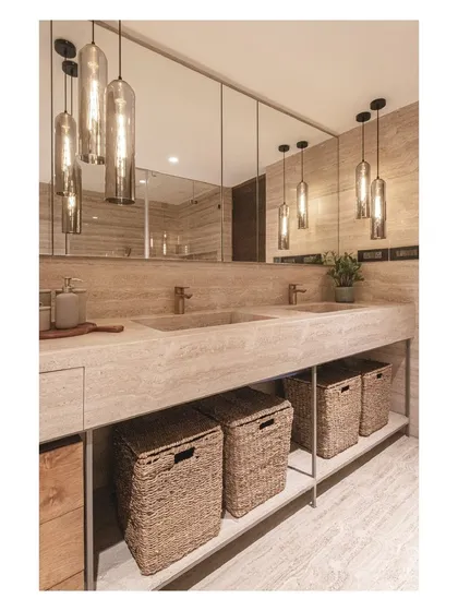 The warm glow from the pendant lights reflects in the large mirror, making the master bath feel spacious and inviting.