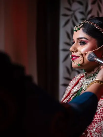A close-up of the makeup artist applying the final touches to the bride, capturing the precision and care that goes into her look.