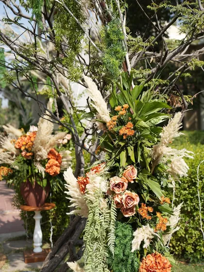 A close-up of a floral arrangement featuring earthy tones, pampas grass, and dried elements. This rustic-chic style is perfect for an outdoor Mehendi or a boho-themed wedding.
