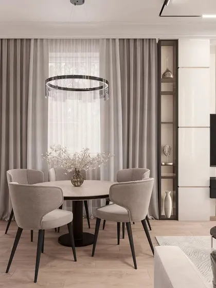 This angle highlights the thoughtful storage solutions that tie the space together. The tall, white cabinetry on the right provides ample storage while blending into the wall, and the open glass shelving adds a decorative touch. The elegant ring chandelier serves as a centerpiece for the dining area.