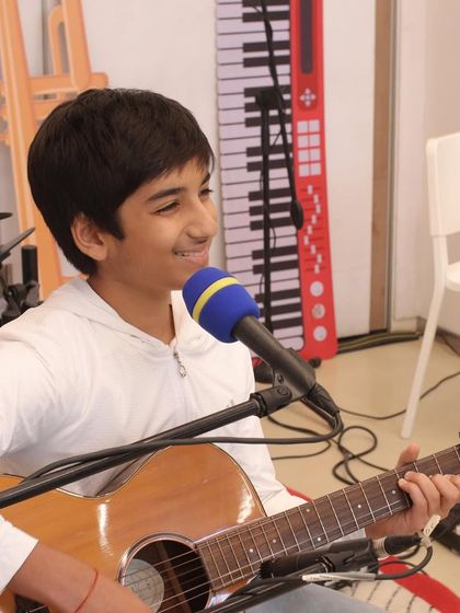 A smiling student enjoying his guitar and vocal performance at the Museum of Solutions. Our goal is to make performing a joyful and rewarding experience.