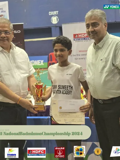 A young champion receiving his trophy at the Mini National Badminton Championship.