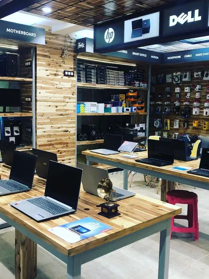 Another angle of the RT Computers showroom, showing the clear demarcation of brands like HP and Dell. The raw, unfinished look of the wooden display walls adds to the industrial aesthetic.