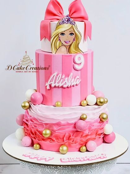 A studio shot of the three-tier Barbie cake for Alisha, showing the ombre ruffles and gold sphere accents.