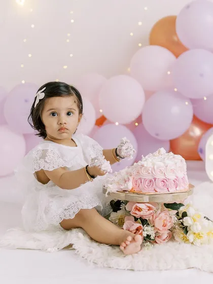A slightly different pose from the same cake smash session, capturing a sweet and thoughtful moment amidst the celebration.