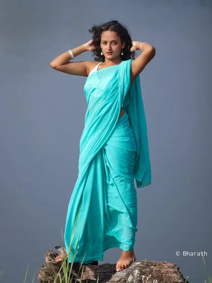 A dynamic shot of the model in the turquoise saree, with her hands in her hair. This image feels free-spirited and modern.