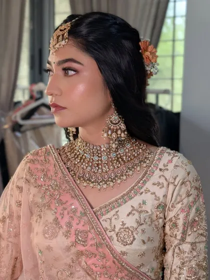 The side profile of Rashi's wedding look, showing the delicate details. Her glowing skin and the soft curls adorned with fresh flowers came together for a truly romantic bridal style.