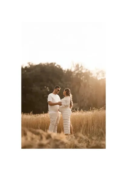 Dancing in a field of gold. This shot captures a moment of joy and connection as the couple shares a dance, their white outfits contrasting beautifully with the warm tones of the wheat field at sunset.