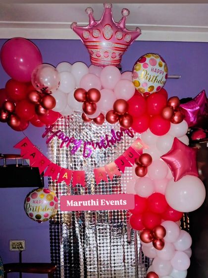 A simple yet beautiful princess-themed birthday decoration with a pink, red, and white balloon arch against a silver shimmer curtain.