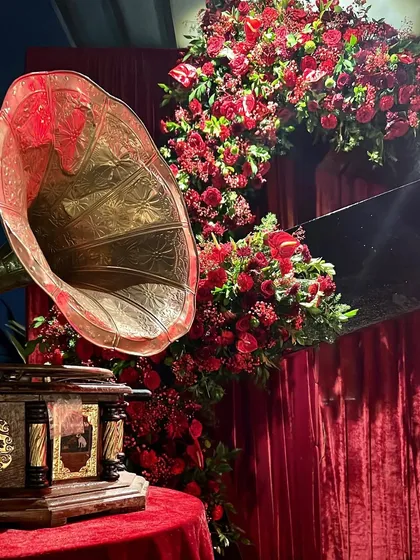 A close-up of the vintage details from the musical night. The antique gramophone paired with a lush arch of red flowers created a stunning focal point.