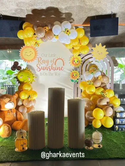 Another angle of the sunny and cheerful baby shower decor. The artificial grass, themed plinths, and bright yellow balloons create a warm and joyful atmosphere.