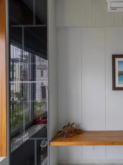 A close-up of a foyer detail, showing a sleek wooden bench next to a black glass display cabinet. The combination of materials adds warmth and sophistication.