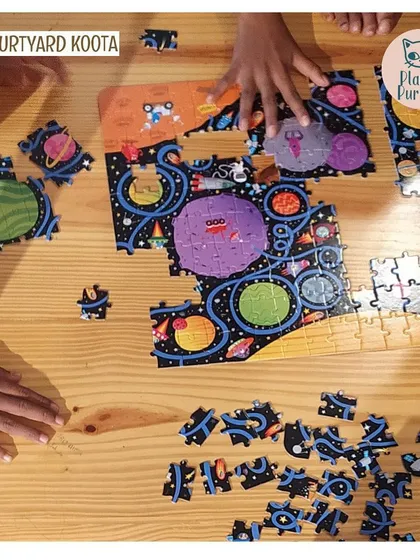 A close up of children's hands working on a space themed puzzle.