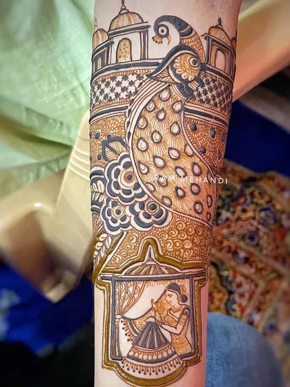 A close-up of the arm portion of a bridal design, showing a bride in a window and a large peacock. The use of negative space and bold lines makes the design stand out.