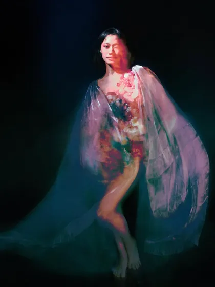 This image uses a slow shutter speed to capture the model's movement, with the flowing fabric creating a colorful, abstract blur. It conveys a sense of dance-like grace.