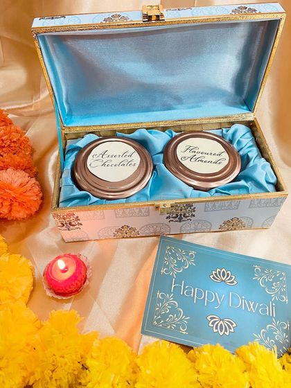 A luxurious Diwali gift box with a beautiful blue satin lining. This chest contains two jars of assorted chocolates and flavoured almonds, perfect for the festive season.