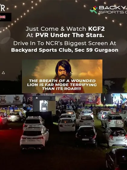 Experience cinema like never before at our PVR drive-in. Here, you can see rows of cars parked for a screening of KGF 2 on NCR's biggest outdoor screen, offering a comfortable and unique movie-watching night under the stars.