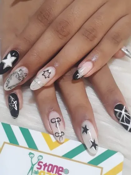 For those who love a bold look. This set features a mix of black and white gel polish with hand-painted stars, bows, and geometric patterns on long almond-shaped extensions.