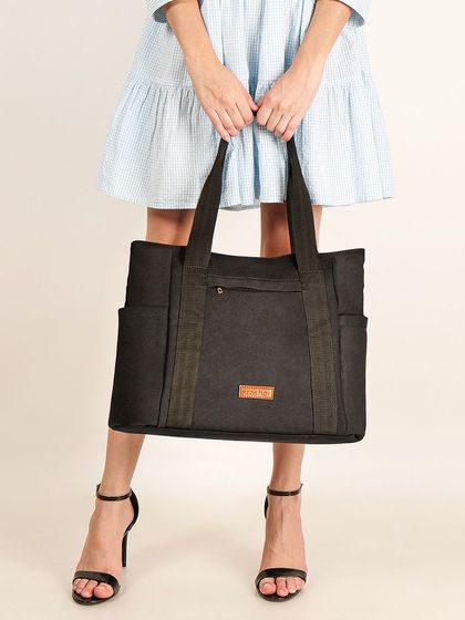 A shot focusing on a large black canvas tote bag held by a model, giving customers a sense of its size and style.