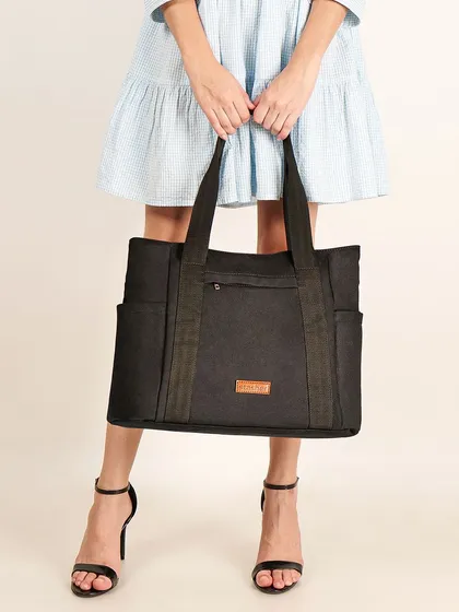 A model holding a large black tote bag. This lifestyle shot shows the bag's size in relation to the person, which is a critical piece of information for online shoppers.