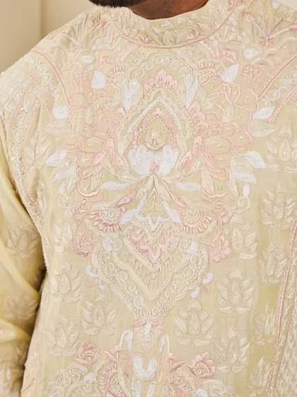 A close-up of the chest, showing the detailed Resham and silk thread embroidery in a traditional pattern on the yellow kurta.