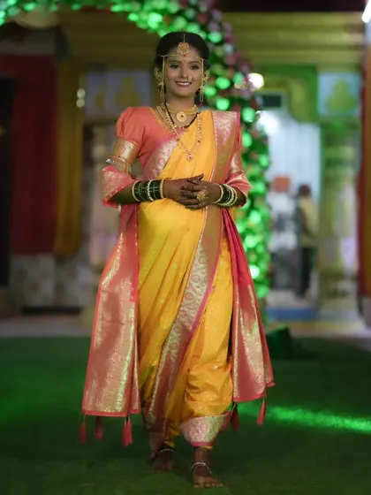 A full-length view of a bride in a stunning yellow and pink Nauvari saree. My draping service ensures the saree is comfortable and perfectly pleated for the entire ceremony.