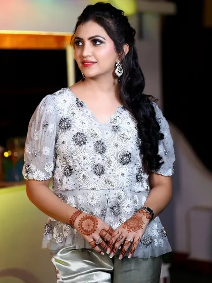 A portrait of a guest at the birthday party, showcasing her elegant top with detailed beadwork and intricate henna on her hands.