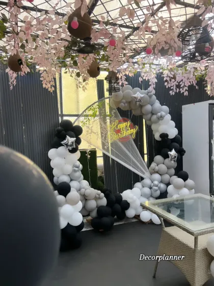 Even from a distance, this setup makes a statement. The contrast of the black and white balloons against the venue's greenery and industrial-chic design works beautifully.