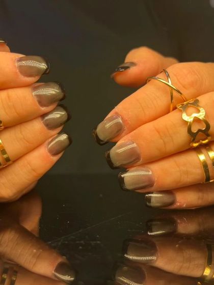 A moody and modern manicure with a sheer grey base and a black French tip.