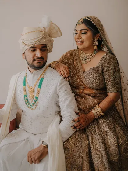 A lovely seated portrait of the couple, showcasing their coordinated outfits and the bride's stunning jewelry.