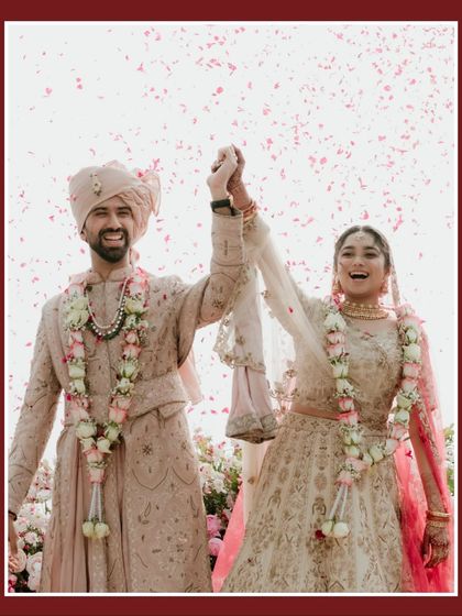 The triumphant "just married" moment. The couple holds hands, their faces lit up with joy as they are showered with flower petals by their loved ones.
