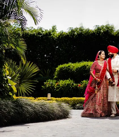 A wide shot of the couple walking hand-in-hand in a lush garden. This photo creates a sense of a fairytale romance on their wedding day.