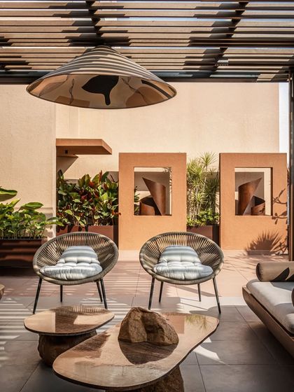 Custom-designed corten steel sculptures are framed like works of art against the terracotta-hued walls. These details add a layer of artistic sophistication and visual interest to the minimalist landscape design.