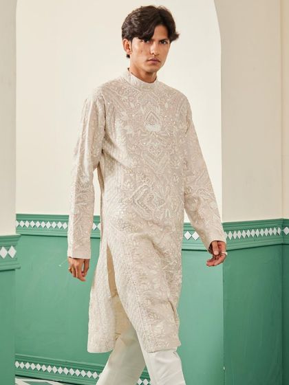The beige kurta in motion, showing the texture of the all-over embroidery.