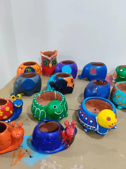 A fantastic collection of hand-painted animal planters, including snails, turtles, elephants, and owls, all decorated by kids at a birthday party.