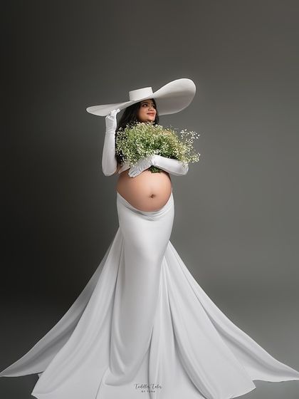 The color version of the elegant white gown with a flowing train and statement hat. Paired with a bouquet of baby's breath, this look is the epitome of grace in bloom.