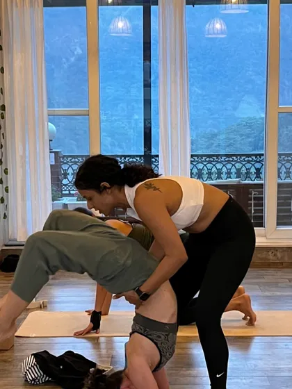 Assisting a student with an inversion during a partner yoga session. These moments of support are what help us grow, both on and off the mat.